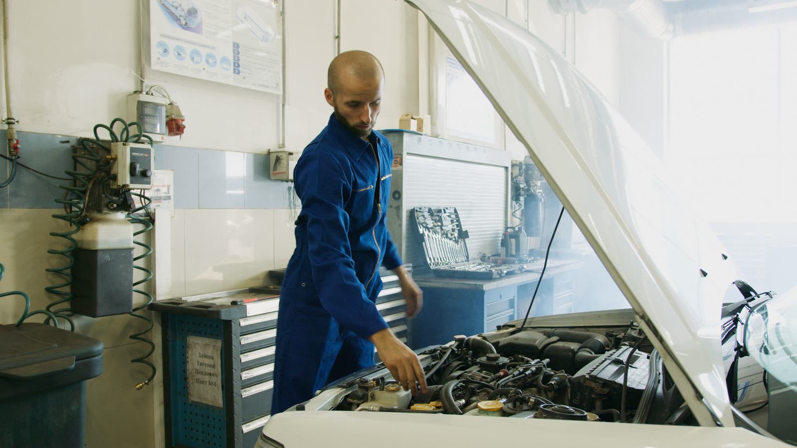Sofiane Belkacem au travail sur un moteur, en bleu de travail