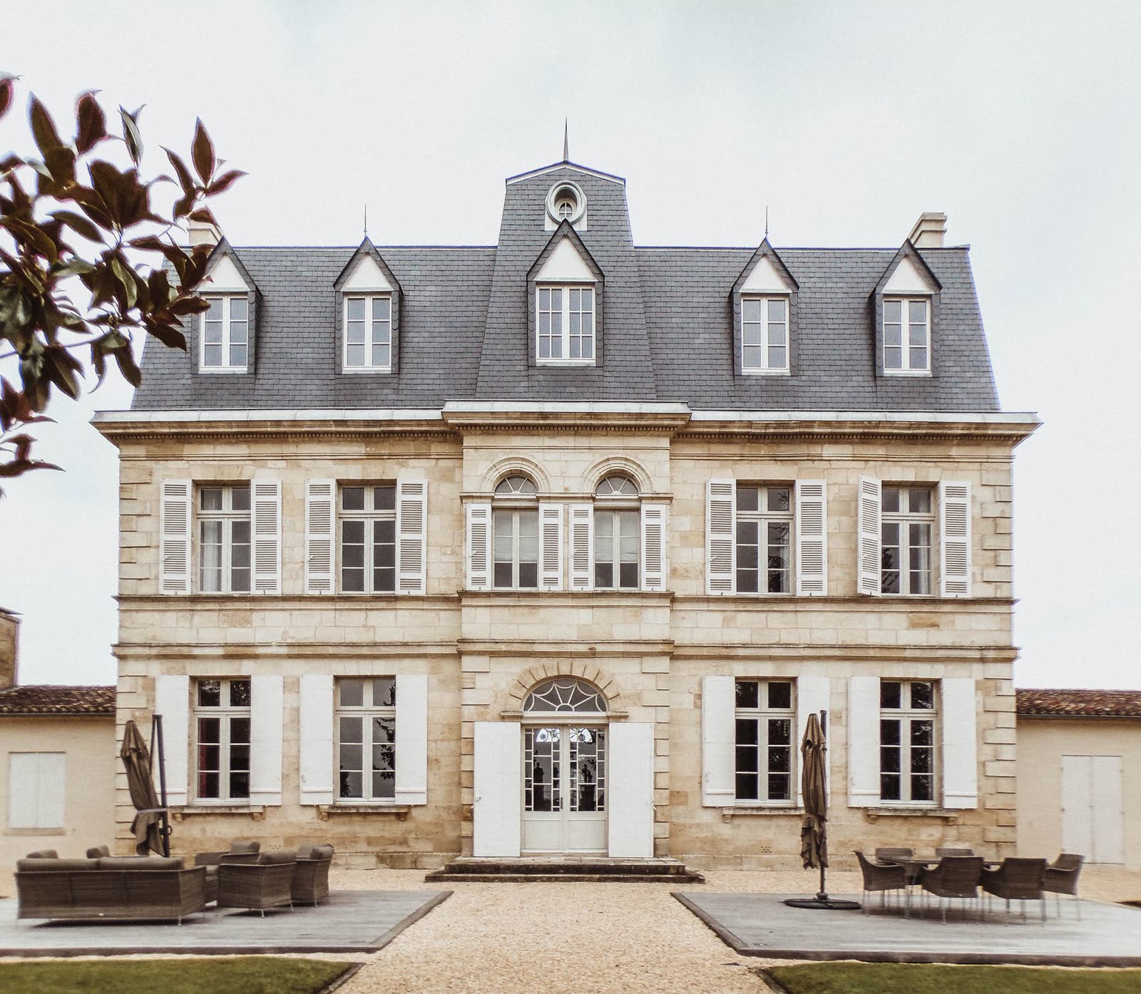 Maison de maître en pierre claire à deux étages, entourée d’un jardin