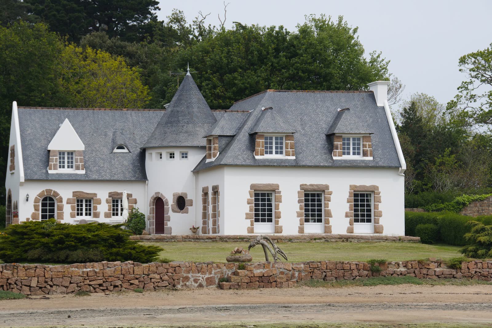 Longère en pierre blanche à toiture d’ardoise, avec une tourelle et un jardin en terrasse