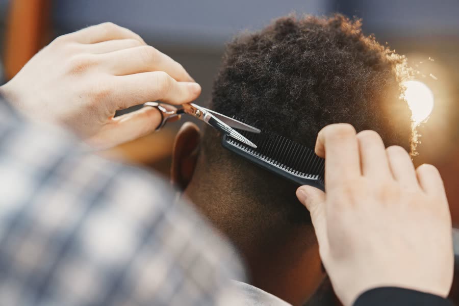 Ciseaux et peigne travaillant une coupe afro, vue de dos