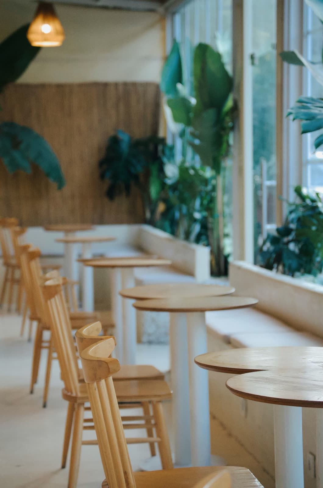 Tables et chaises en bois clair devant de grandes fenêtres
